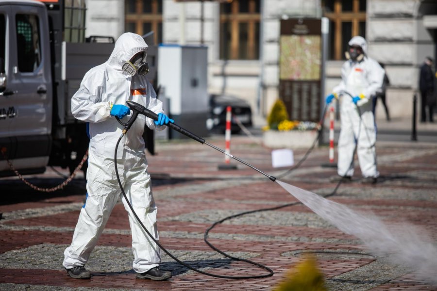 Ekipa w maskach i kombinezonach ochronnych w centrum miasta - foto